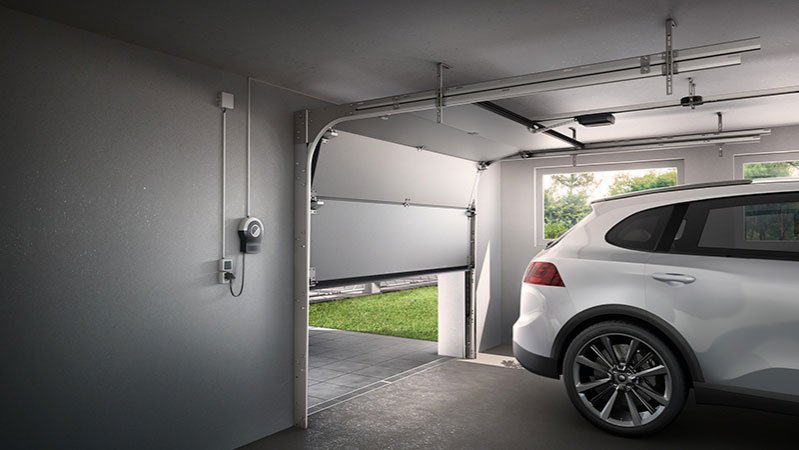 Modrner SUV in einer Garage, die gerade durch einen Garagentorantrieb geöffnet wird